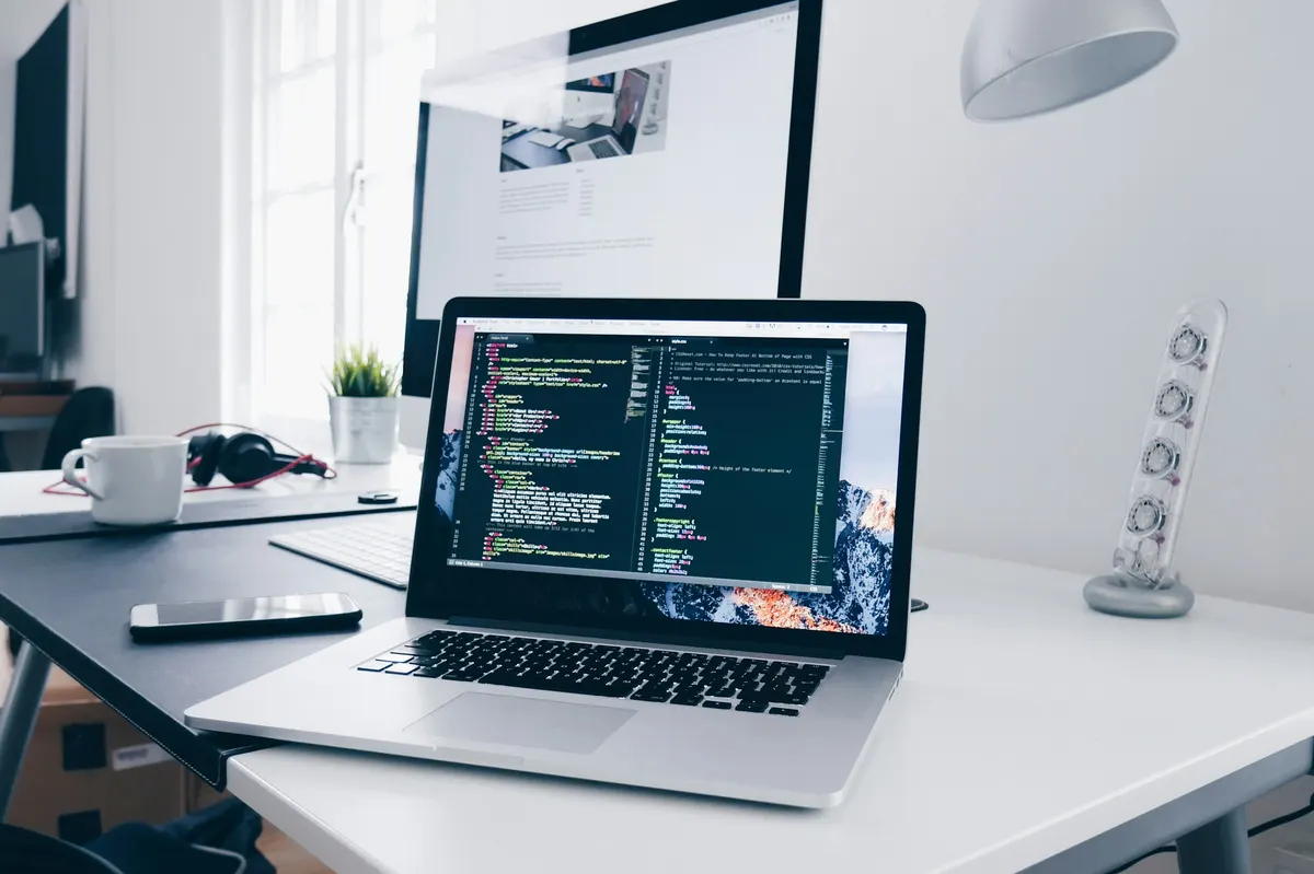 A laptop and monitor at a software-development workstation.