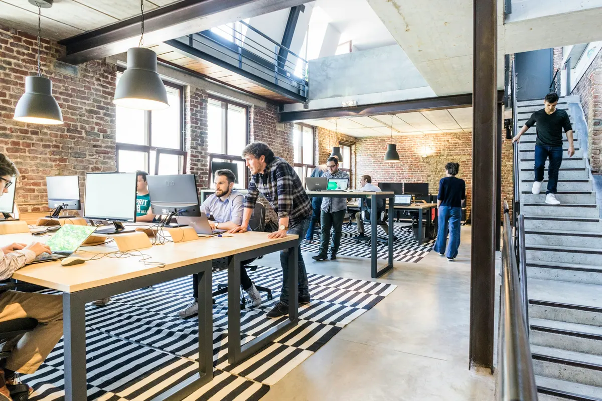 A team collaborating at shared desks in a naturally lit operations office.