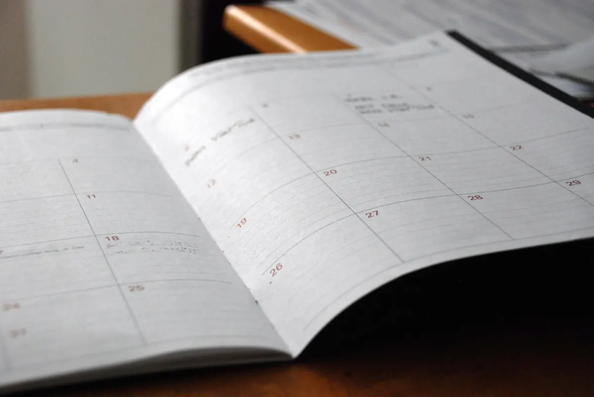 An open monthly planner on a wood desktop, illustrating scheduling and availability.