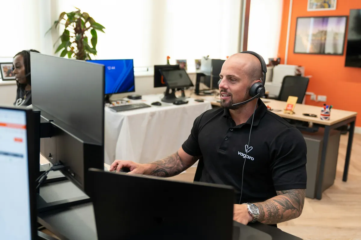 A customer-support specialist wearing a headset while working at a computer.