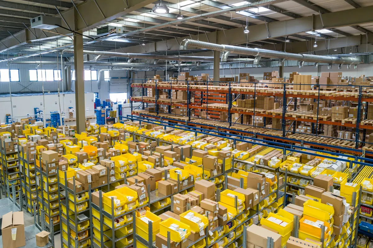 An organized distribution warehouse with storage racks, boxes, and stock bins.