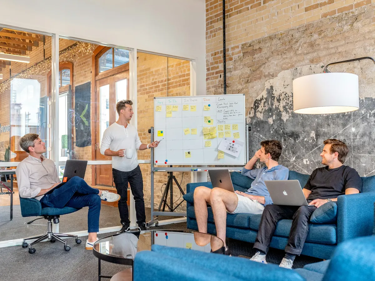 A team reviewing a plan on a whiteboard in a naturally lit studio.